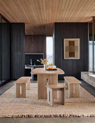 #size::2-6--x-8- #size::3--x-5- #size::6--x-9- #size::8--x-10- #size::9--x-12- #size::10--x-14- #size::12--x-15- | The Hagan rug lays under a rectangular wooden dining table, tow dining benches, and two dining stools