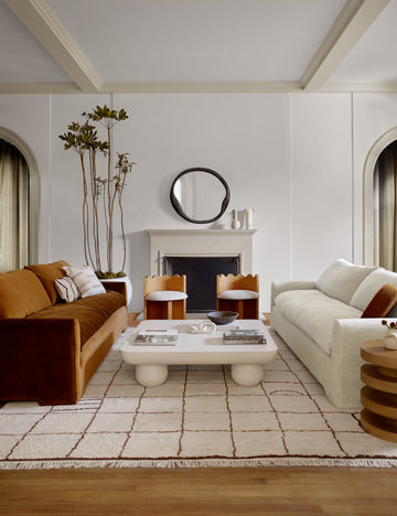 #color::Cognac-Velvet | The Rupert cognac velvet sofa sits across an ivory linen sofa with two scalloped chairs and a square white coffee table in between