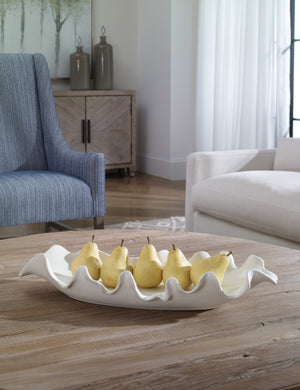 Beline low-profile ruffled long decorative bowl styled on a coffee table filled with pears.