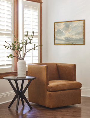 The golden framed Study of Clouds with a Sunset near Rome Wall Art by Simon Alexandre Clement Denis is hung in the corner of a living room with a black wooden side table, a brown leather accent chair, and a white ribbed vase