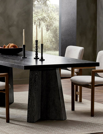 #color::brown #size::96-W | Hallen angular leg sculptural dining table styled with upholstered wood frame dining chairs, candlesticks and light colored rug.