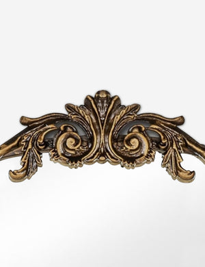Detailed view of the traditional scroll detailing on the top of the Tulca arched gold mirror with flat bottom edge.