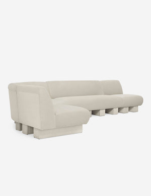 Angled view of the Lena left-facing white boucle sectional sofa with upholstered beam legs.