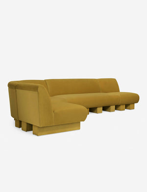 Angled view of the Lena left-facing yellow velvet sectional sofa with upholstered beam legs.