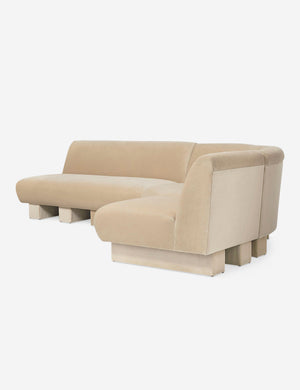 Angled view of the Lena right-facing beige velvet sectional sofa with upholstered beam legs