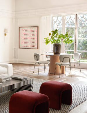 The See Through cherry red and white wall art hangs on a white wall in a room with a living area and breakfast nook