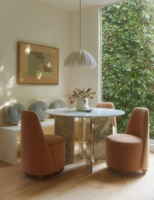Nita pleated shade pendant light hung above a round marble dining table.