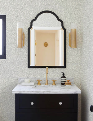 The Dainty Leaves floral Wallpaper by Rylee + Cru is in a bathroom with a black wooden marble topped sink and a black framed arched mirror