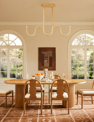 Noor sculptural, wavy linear chandelier hanging above a dining table