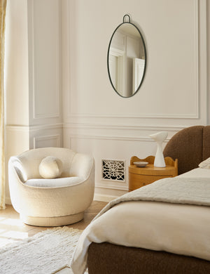  Fern scalloped back boucle upholstered swivel chair styled in a corner of a bedroom
