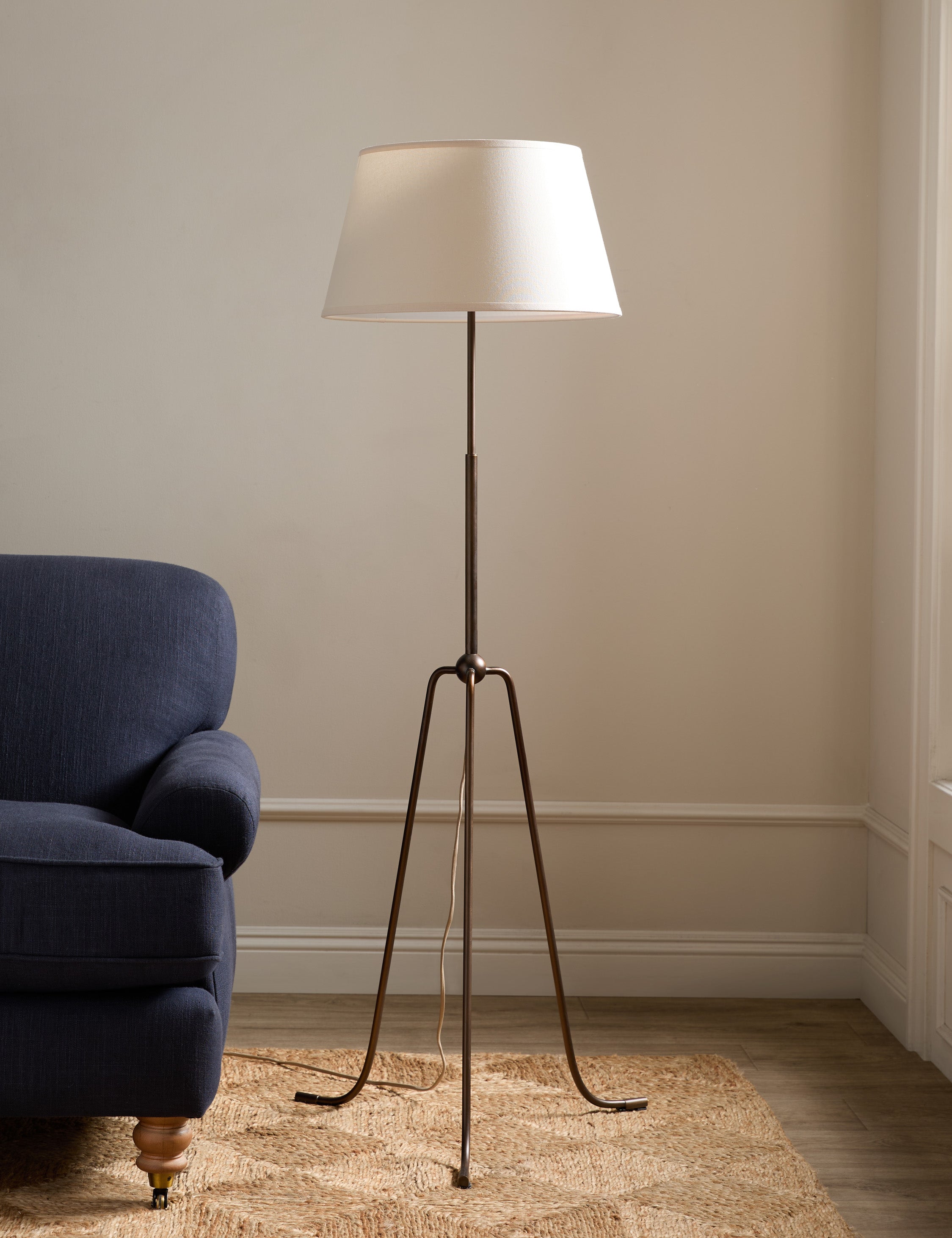 #color::aged-brass | Francis slim frame tripod floor lamp by Heidi Caillier styled next to a sofa