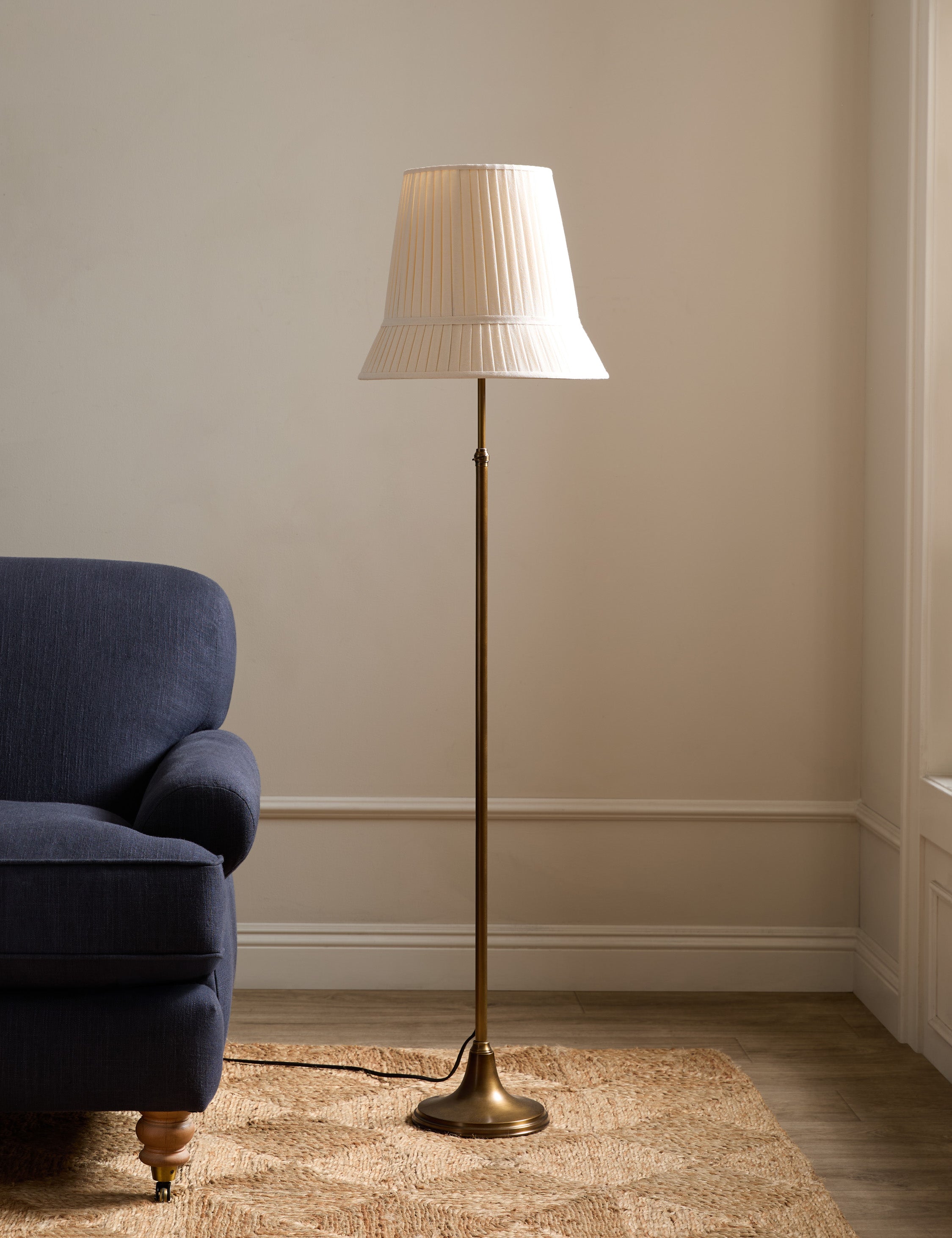 #color::aged-brass | Lily slim metal stem adjustable height floor lamp by Heidi Caillier styled next to a sofa