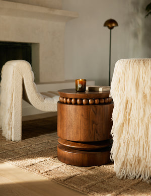 Coco round drum beaded wood side table by Carly Cushnie styled with two armless accent chairs.