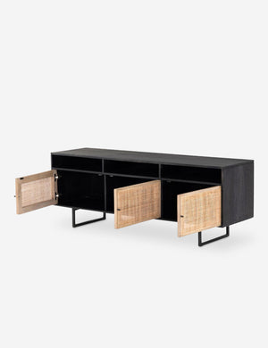 Angled view of the Hannah black mango wood media console with its three cane doors open, revealing the inner shelving.