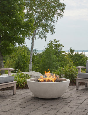 The Benno fog fire bowl sits in an outdoor space next to outdoor lounge furniture
