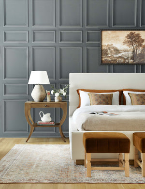 The Este nightstand is in a bedroom with accented blue walls next to a natural linen framed bed
