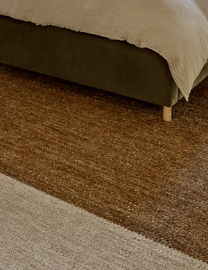 Close up of the wilcox rug laying underneath a jade green velvet framed bed