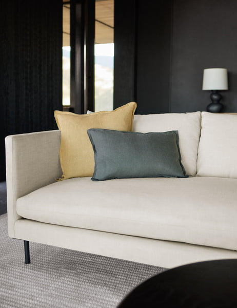 #color::marigold #style::square #fill type::with-feather-down-insert #fill type::pillow-cover-only | The arlo marigold square pillow sits on a white linen sofa with a gray throw pillow in front of it