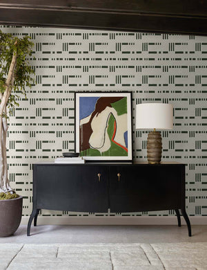 The Anabella black wood console table with silver drawer pulls sits underneath a geometric wall art against black and white patterned wallpaper.