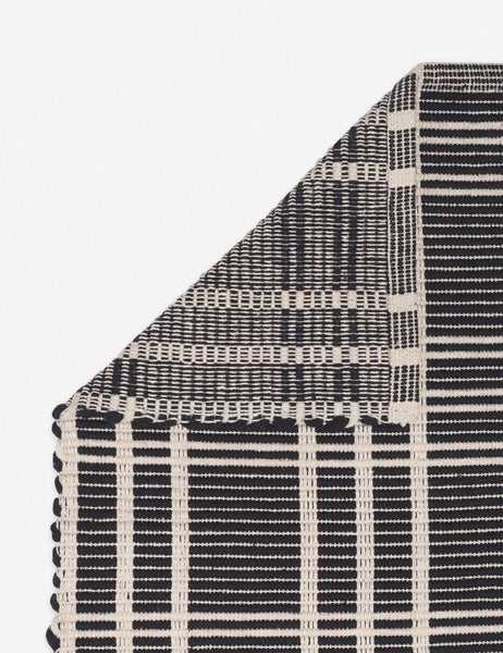 #size::1-9--x-2-10- #size::2--x-5- | Corner shot of the Rika black and white cotton machine washable mat with checkerboard pattern