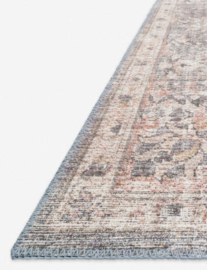 Angled close-up of the medallion patterns on the corner of the Roze grey and apricot power-loomed rug