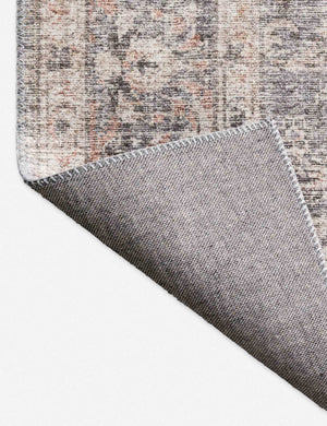Close-up of the corner of the Roze grey and apricot power-loomed rug with medallion patterns with the bottom folded over
